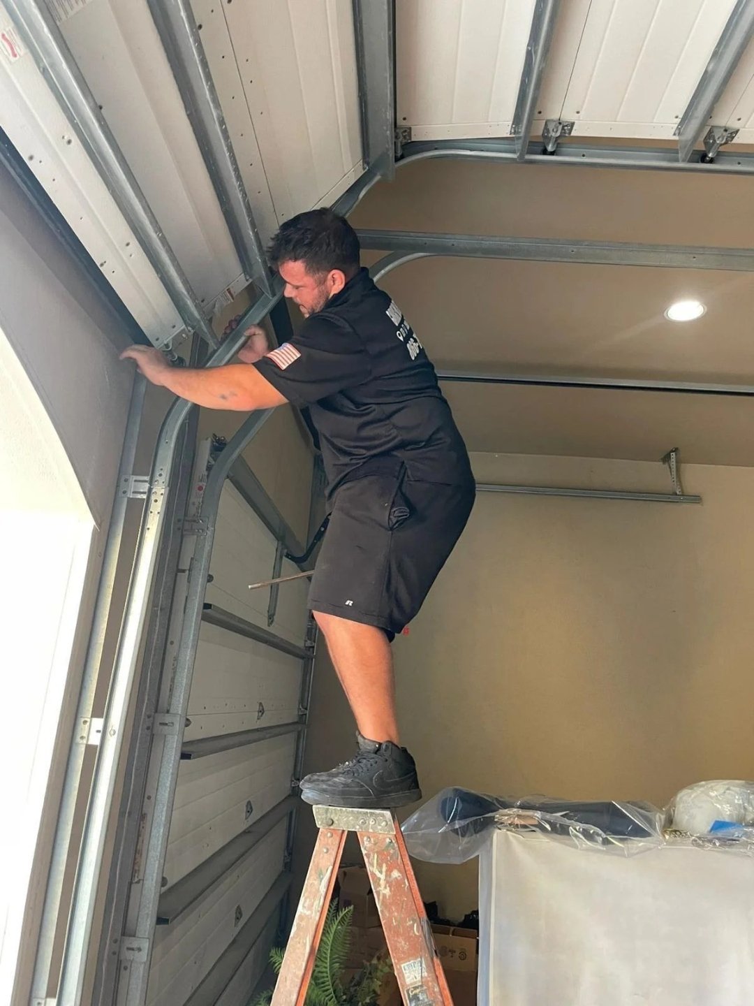 Technician on a stepladder reaching the side track beside the wall