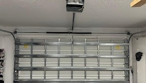 Closed sectional garage door seen from inside, with the opener rail and light above it