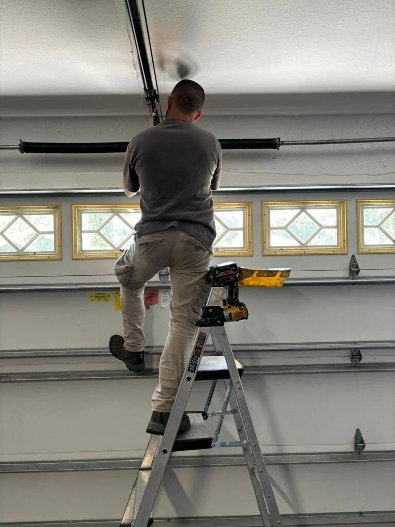 Technician on a stepladder at a garage door with diamond-pattern window panels