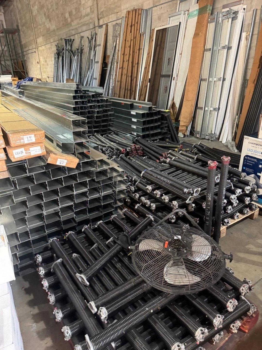 Stacks of steel track and door hardware stored in a warehouse