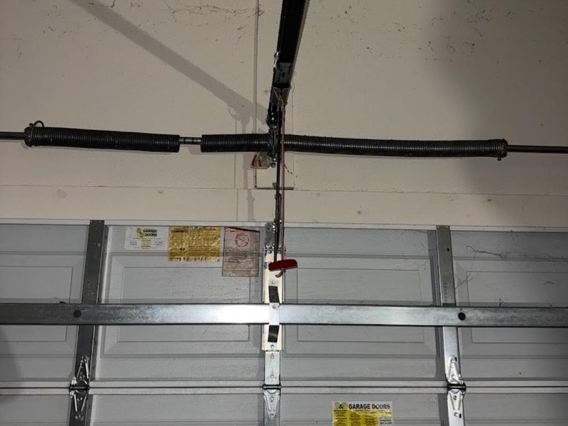 Torsion spring stretched across the top of a sectional garage door above a steel top strut